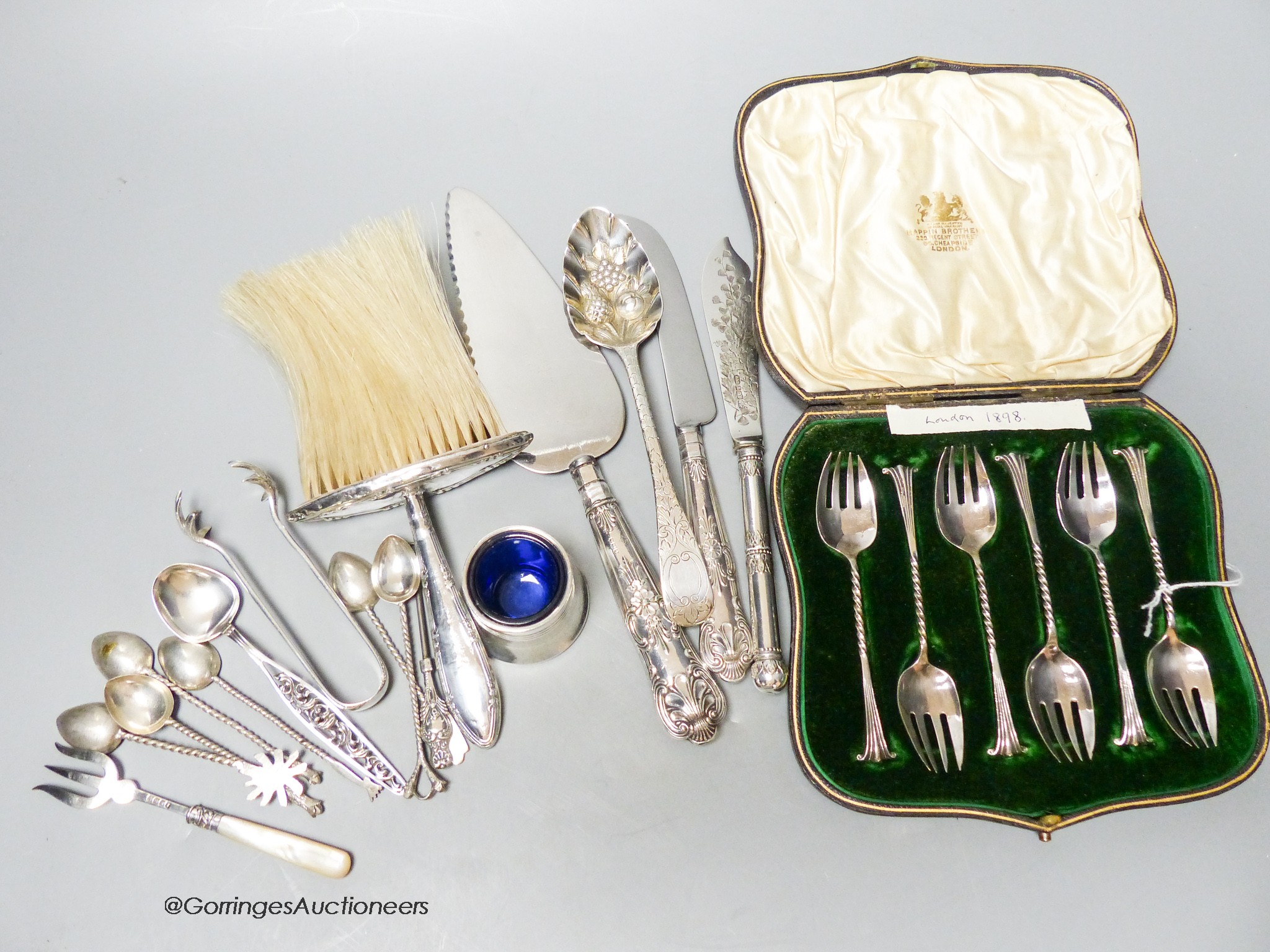 A set of six Victorian silver cake forks, a George III silver berry spoon (later embossed), a pair of silver sugar tongs and a spoon and sundry items